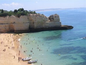 A beach with clear water, people swimming, and boats near the shore. - CASA GALERIA, fantastic vacation home in a nature reserve near the beach with pool (Lagoa)