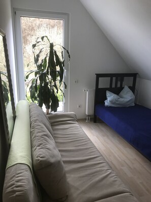 Um quarto com cama, janela e vista para vegetação, além de um radiador.