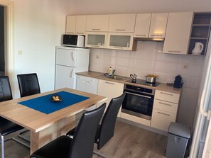 Una cocina compacta con armarios blancos, microondas, lavavajillas y horno pequeño.