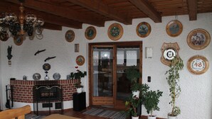 Ein gemütlicher Raum mit Holzbalkendecke, Kamin aus Ziegelsteinen und einem Esstisch mit Stühlen.