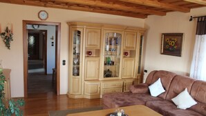 Ein Wohnzimmer mit einem braunen Sofa, einem Holztisch und einer Vitrine mit Glastüren.