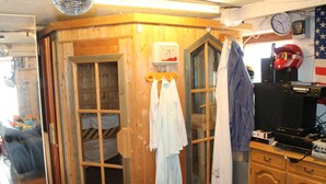 Eine Holzhütte mit Bett, Fenster, Uhr und Fernseher.