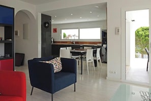 Una sala de estar moderna con un sofá azul, un sillón rojo y una mesa de centro de vidrio.