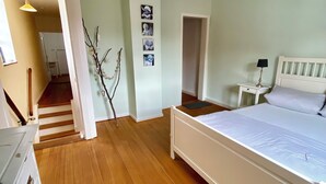 A bedroom with a wooden floor, a white bed, a nightstand, and a staircase leading to another room. - Lovingly furnished holiday home in the small wine-growing village (Landau in der Pfalz)