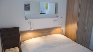 A bedroom with a bed, a headboard, a bedside table, a mirror, and a wardrobe. - family-friendly, comfortable accommodation, 2 terraces, 200 m to the beach (Neustadt in Holstein)