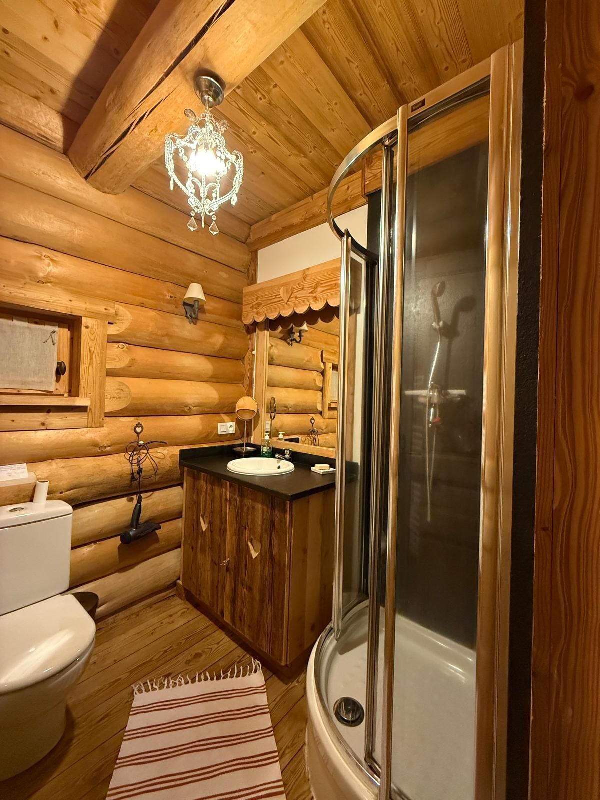 Een houten badkamer met toilet, wastafel en douche.