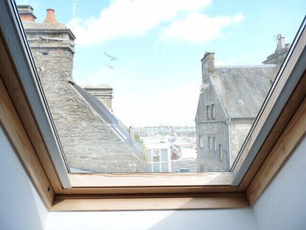 A skylight window with a view of stone buildings and a lighthouse.