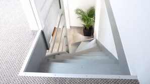 Eine moderne Treppe mit Metallgeländer, die zu einer Zwischenebene mit einem Blumentopf führt.