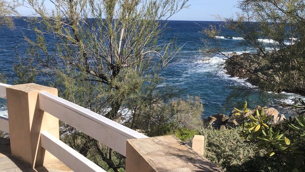 Un balcon avec vue sur l’océan et la côte rocheuse.