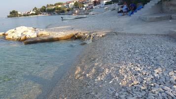 Guests can enjoy access to a pebbled beach with clear blue water and a rocky shoreline.