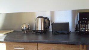 Eine Küchenarbeitsplatte mit Kaffeemaschine, Toaster, Wasserkocher und einer dekorativen Schale.