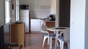 Eine kompakte Küche mit Mikrowelle, Kühlschrank und einer kleinen Essecke mit zwei Stühlen und einem Tisch.
