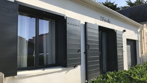 A building with a white facade, black shutters on the windows, and a sign that reads "L'Escalier".
