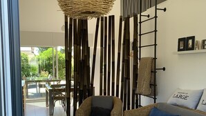 A modern living room with wicker furniture, a black coffee table, and a large woven light fixture.