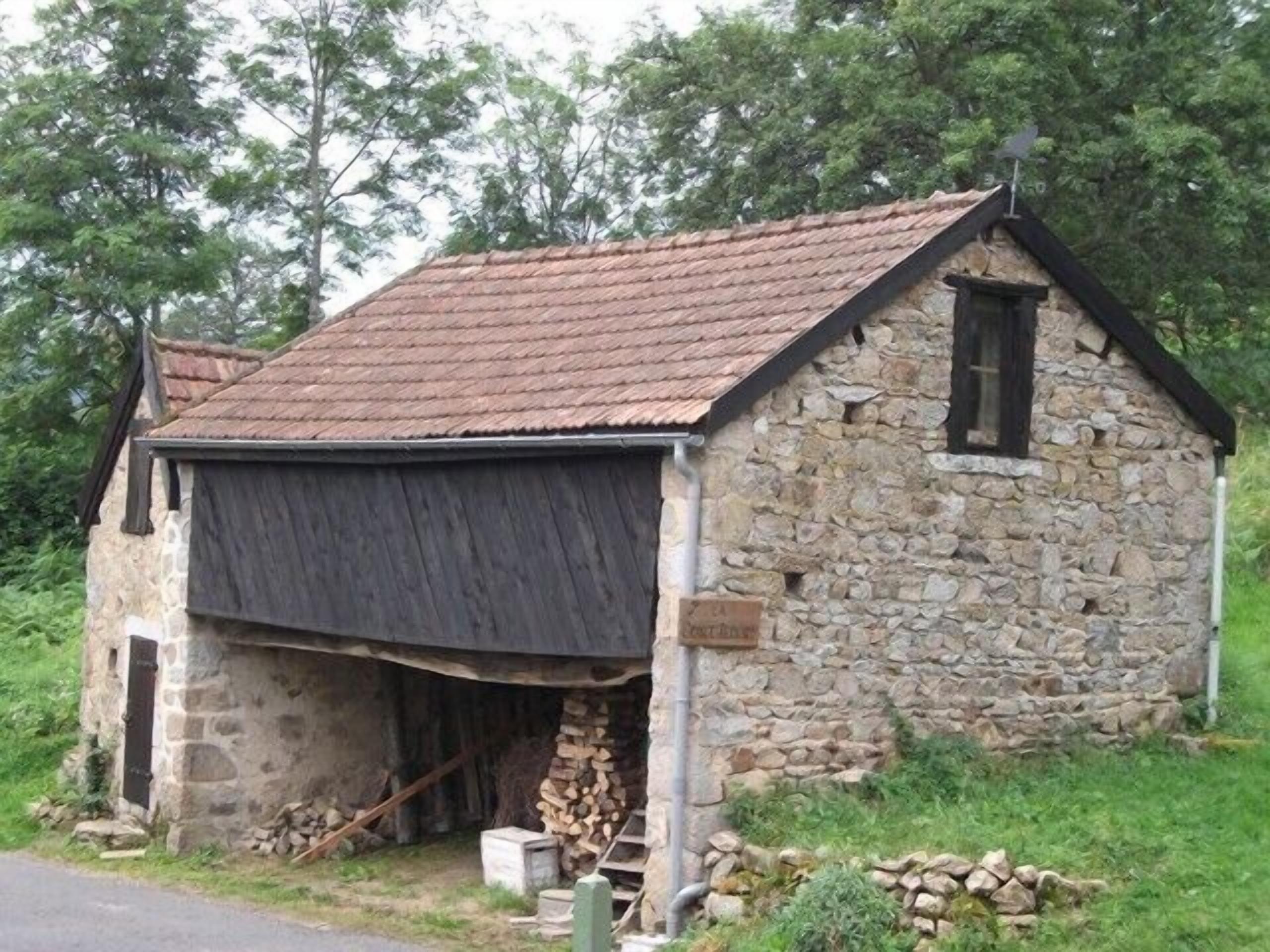 A stone building with a sloped roof and a wooden door.