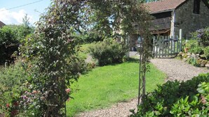 A stone building with a gravel path leading to a wooden gate.