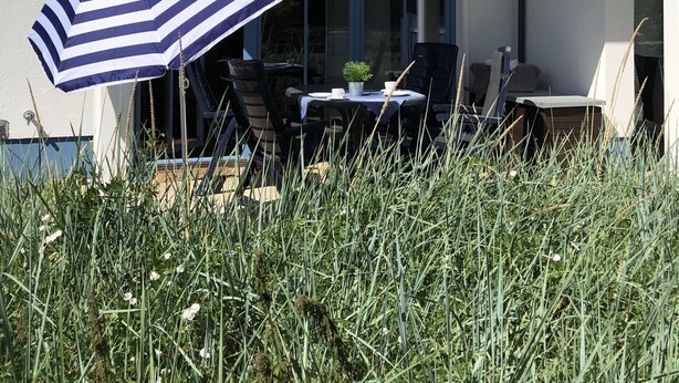 A patio with a table and chairs, an umbrella, and a view of a building with a balcony.