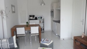Een moderne, compacte leefruimte met een eethoek, kitchenette en een klein zithoekje.