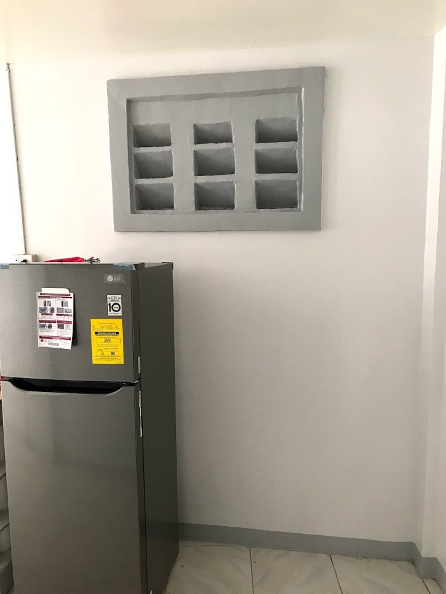 Eine kleine Küche mit einem Einbaukühlschrank und einem Fenster mit Gittermuster.