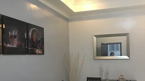Un comedor con una mesa rectangular, seis sillas y un florero con pastos altos.