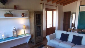 Un salon avec un canapé blanc, une table basse en bois, un meuble et une étagère ornée d’objets décoratifs.