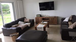 A modern living room with two sofas, a coffee table, and a TV mounted on the wall. - Large house with exceptional sea views in a protected environment (Plouharnel)