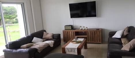 A modern living room with two sofas, a coffee table, and a TV mounted on the wall.