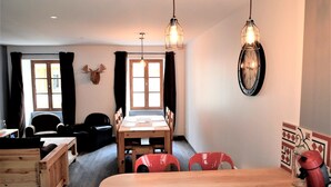 A dining area with a wooden table and chairs, a clock on the wall, and a deer head decoration.