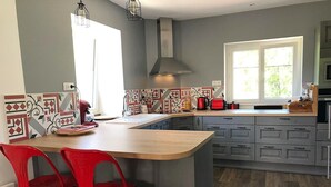A modern kitchen with a central island, grey cabinets, and a window providing natural light.