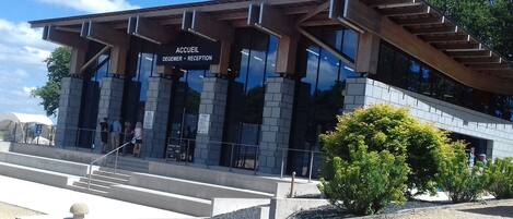 A modern building with a reception area, large windows, and a staircase leading up to the entrance.