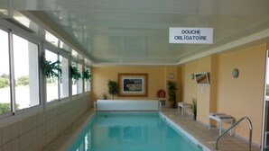 Una piscina interior con un letrero que dice "DOUCHE OBLIGATOIRE".