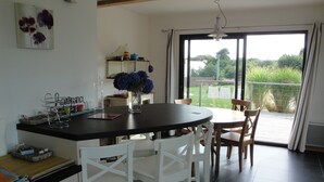 A kitchen with a dining area, a large window, and a view of greenery outside.
