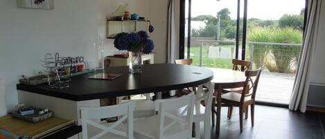 A kitchen with a dining area, a large window, and a view of greenery outside.