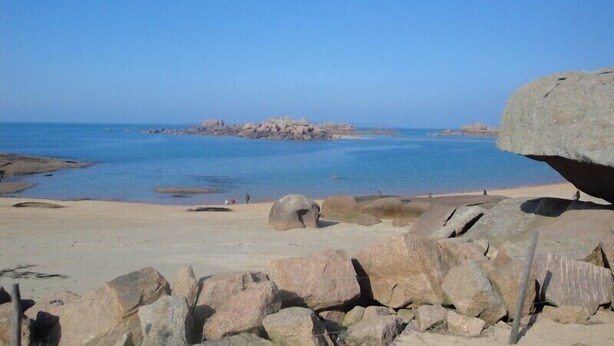 A rocky beach with large boulders and calm water.