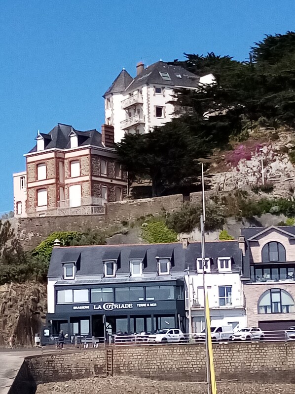 A historic building with a stone facade and multiple windows, located on a hillside with a restaurant named "LA COTRIADE" in the foreground. - Panoramic sea view 250° from all 10 windows! Classified as 4* furnished tourist accommodation. WIFI Fiber (Pléneuf Val André)