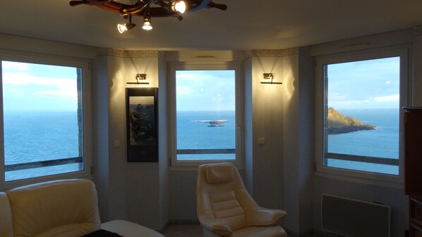 A room with a view of the sea, a chair, and a ceiling light fixture. - Panoramic sea view 250° from all 10 windows! Classified as 4* furnished tourist accommodation. WIFI Fiber (Pléneuf Val André)