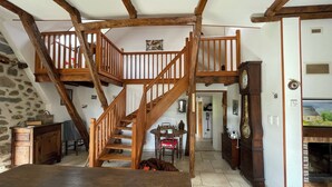A rustic interior with a wooden staircase, stone walls, and a fireplace. - Fully restored stone and slate barn in a typical village (Lacroix-Barrez)