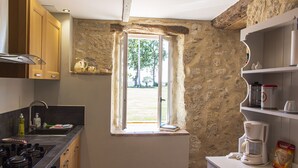 Eine Küche mit Steinwand, Holzschränken, einem Fenster und einer Kaffeemaschine.