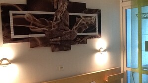 A hotel room with a bed, a wall-mounted artwork, and two wall sconces. - BEAUTIFUL WATERFRONT APARTMENT - BREATHTAKING MARINA AND SEA VIEWS! (Courseulles-Sur-Mer)