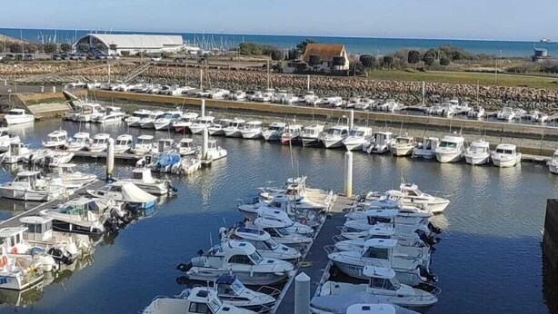 A marina with numerous boats docked in a row, a clear sky, and a view of the coastline. - BEAUTIFUL WATERFRONT APARTMENT - BREATHTAKING MARINA AND SEA VIEWS! (Courseulles-Sur-Mer)