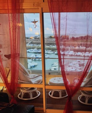 Relax in a tranquil space with a marina view, featuring a large window, two comfortable rocking chairs, and a traditional design.