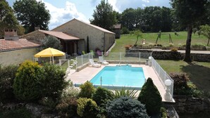 A swimming pool surrounded by a fenced area with a stone building nearby. - Country house with heated swimming pool with solar panels. (Mauroux)