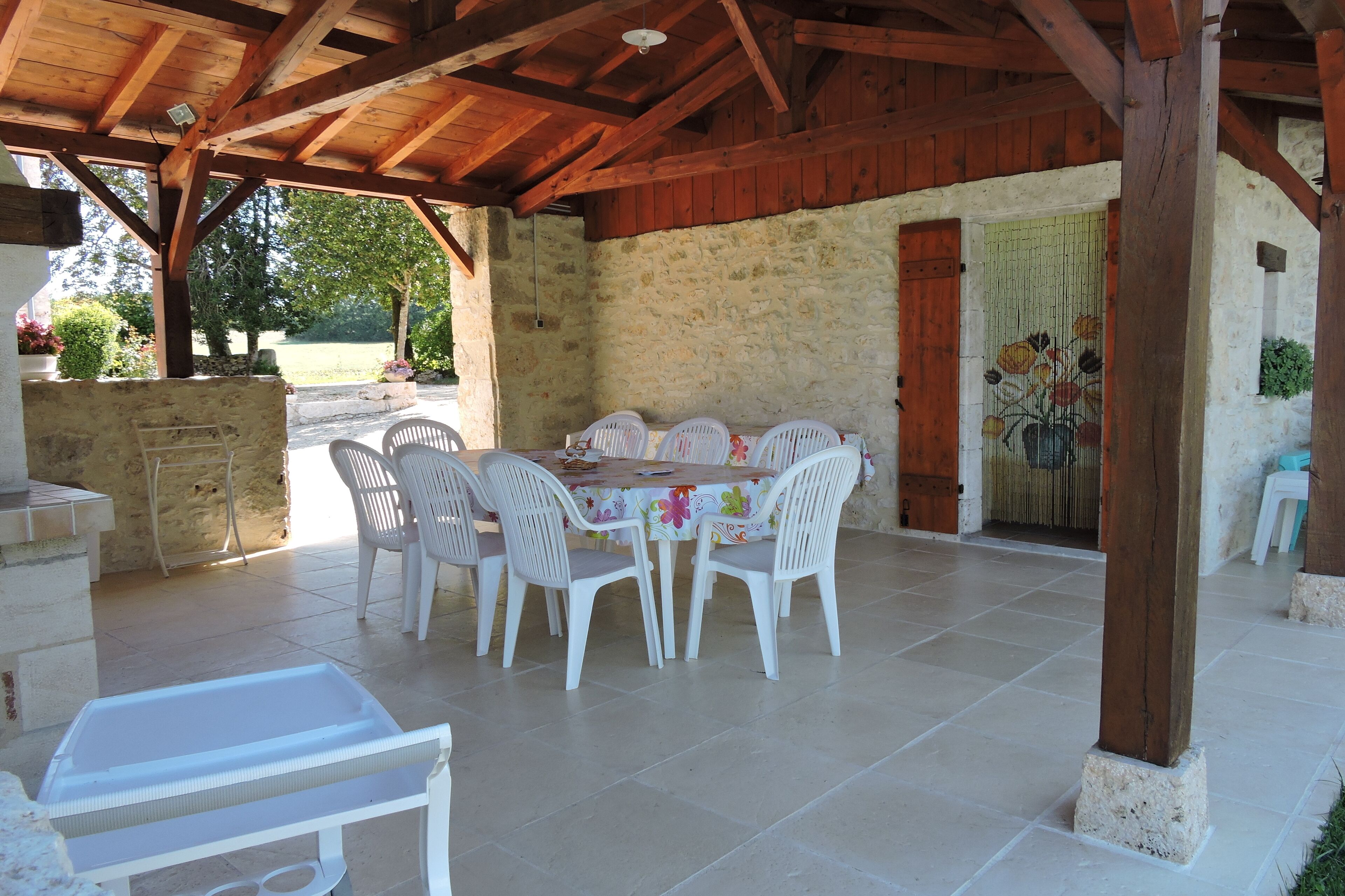 Eine Terrasse im Freien mit einer Steinwand, Holzboden und einem Tisch mit Stühlen.