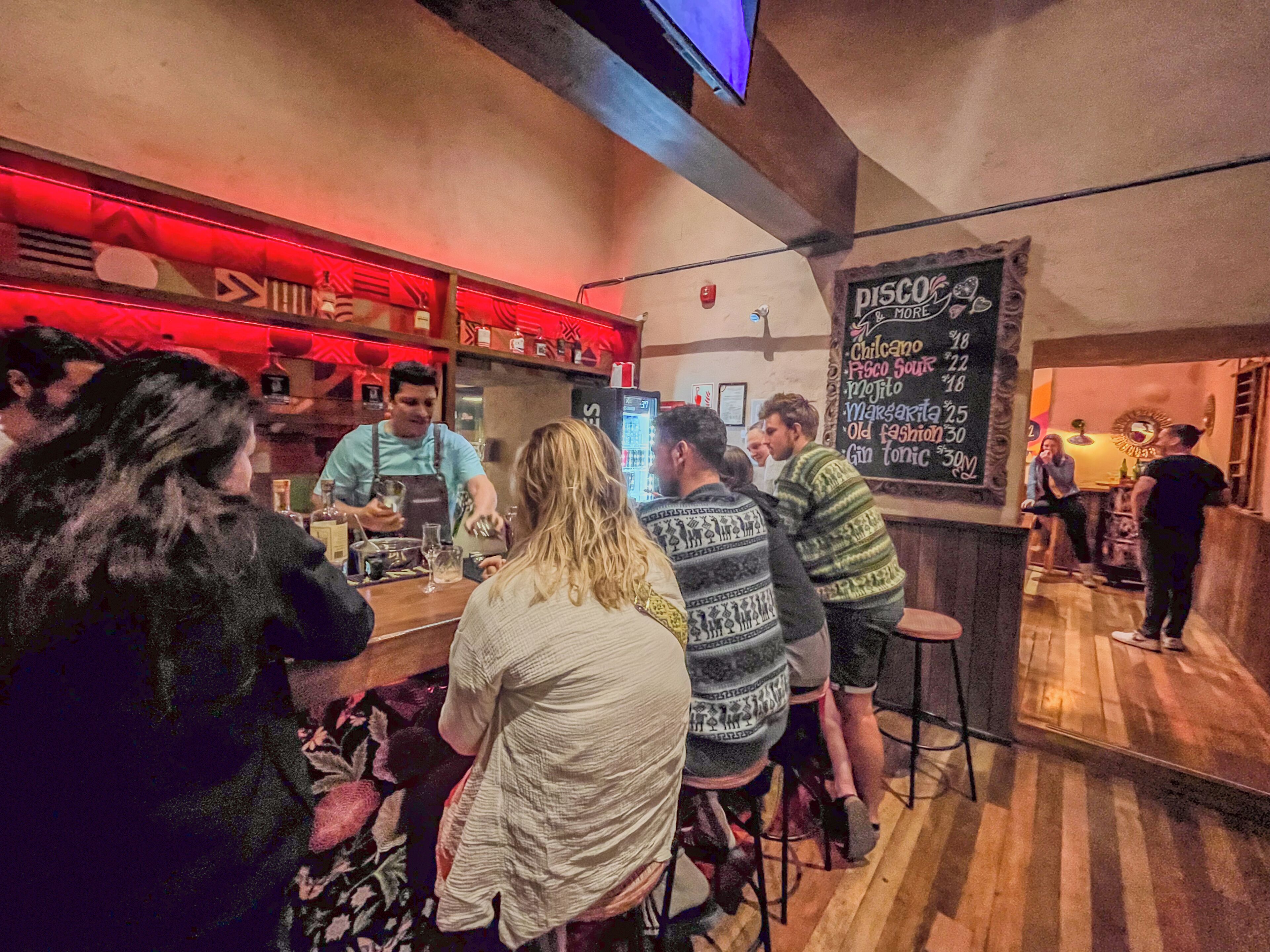 Zona de bar con un menú en pizarra que enumera bebidas y una barra de madera.