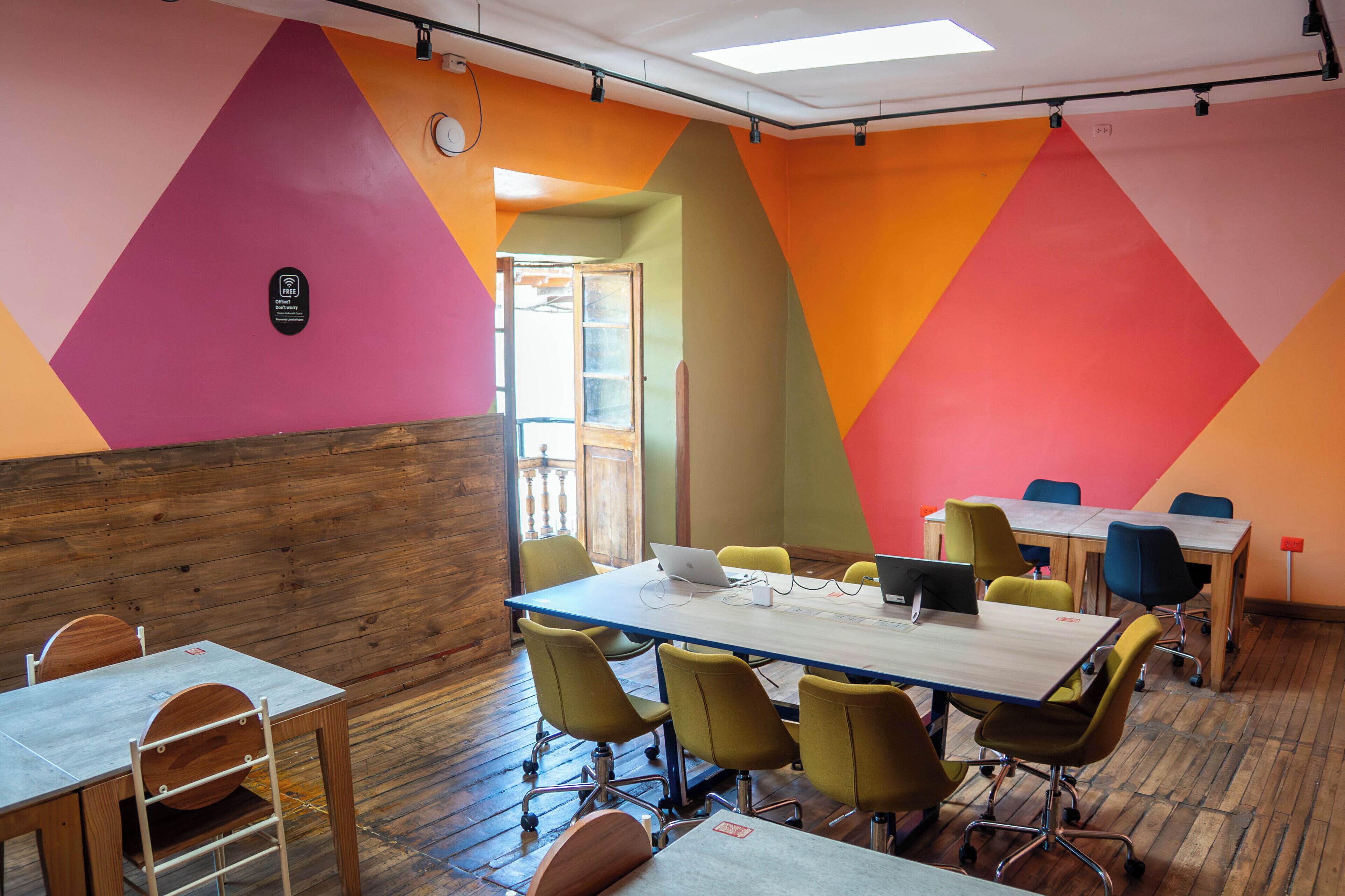 A conference room with a long table, yellow chairs, and a wooden accent wall.