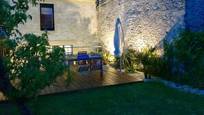 Ein Innenhof mit Holzterrasse, Sitzgelegenheiten im Freien und einer Steinmauer.