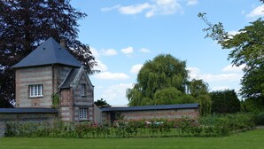 Un bâtiment en pierre avec une tour et un grand arbre en arrière-plan.
