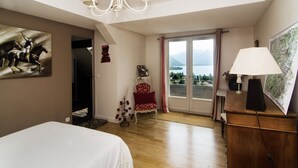 Un dormitorio con cama, candelabro, silla, escritorio y vistas al exterior.