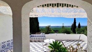 A terrace with a checkered floor, a patterned bench, and a view of a green landscape with trees. - beautiful villa with private pool, bbq, wifi, 10 mins from the sea and  golf  (alcantarilha)