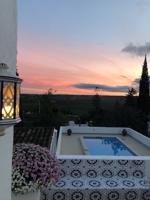 A rooftop pool with a view of the countryside at sunset.